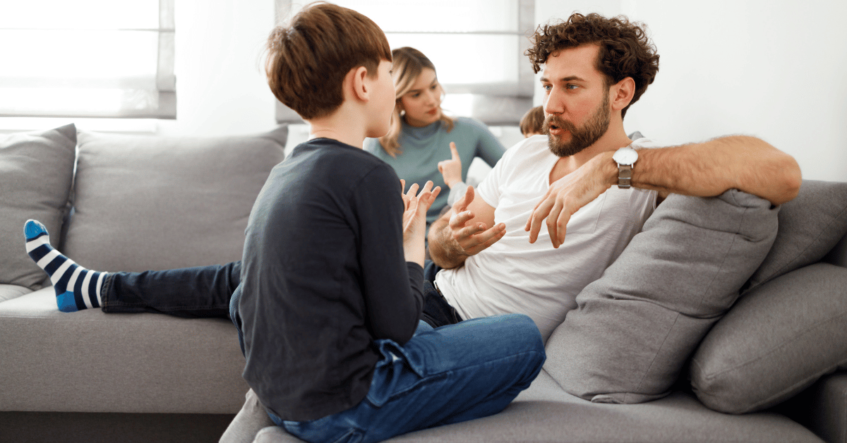 father talking to young son on couch