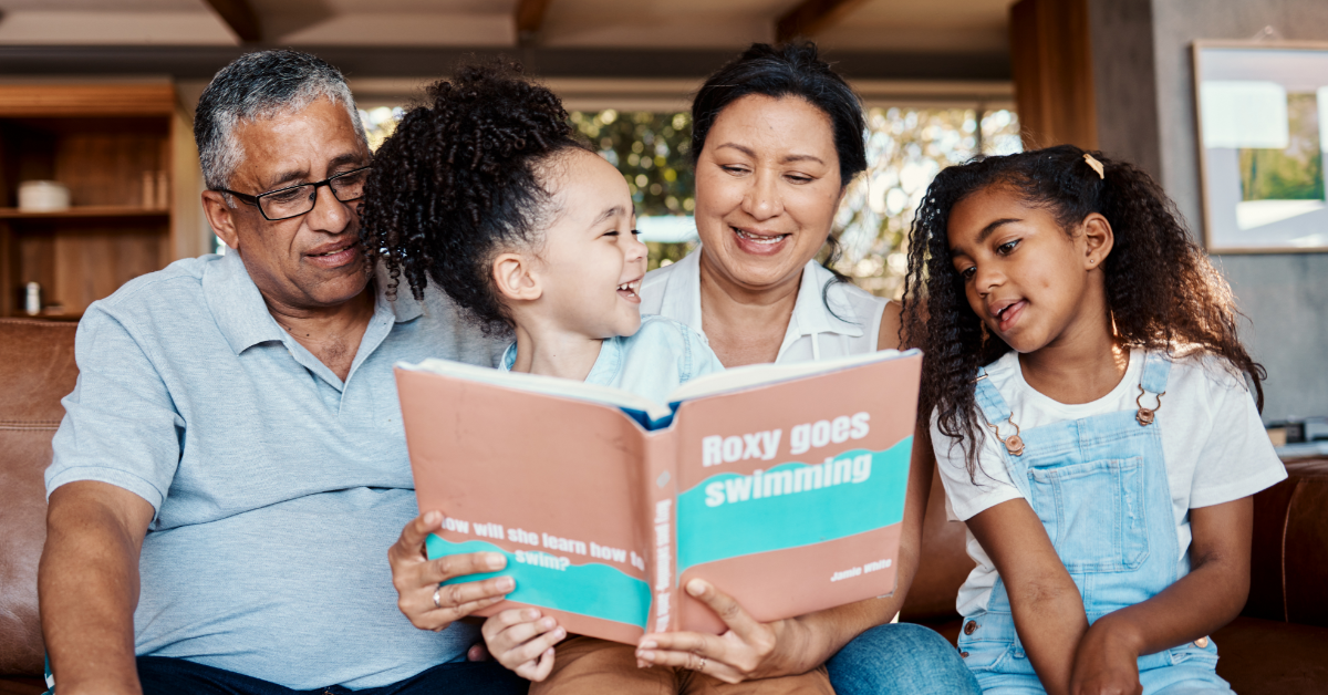 Grandparents reading a book to grandchildren