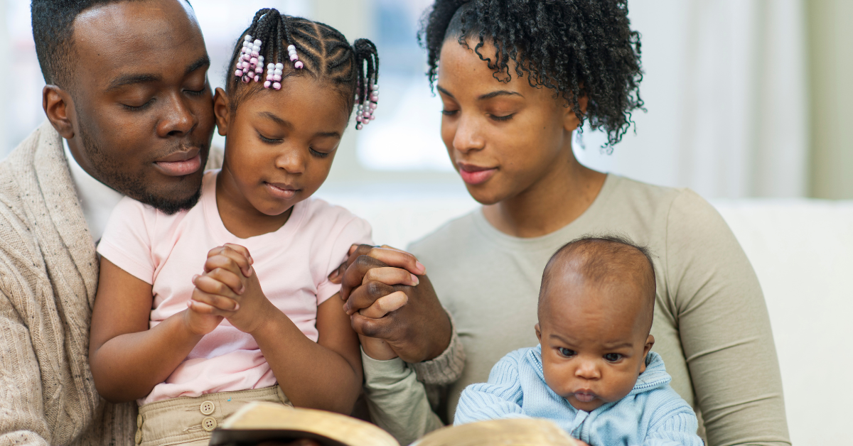 Parents praying together with their young children