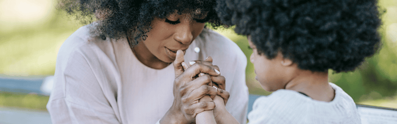 african american mom praying with toddler