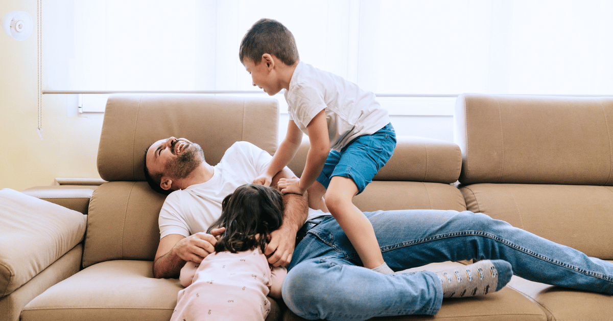 Father playing on couch with two small children