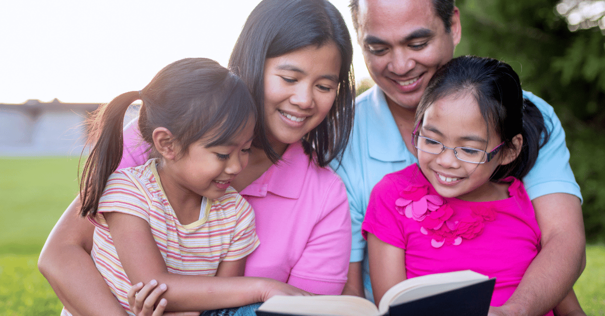 Mom and dad reading book with two young daughters