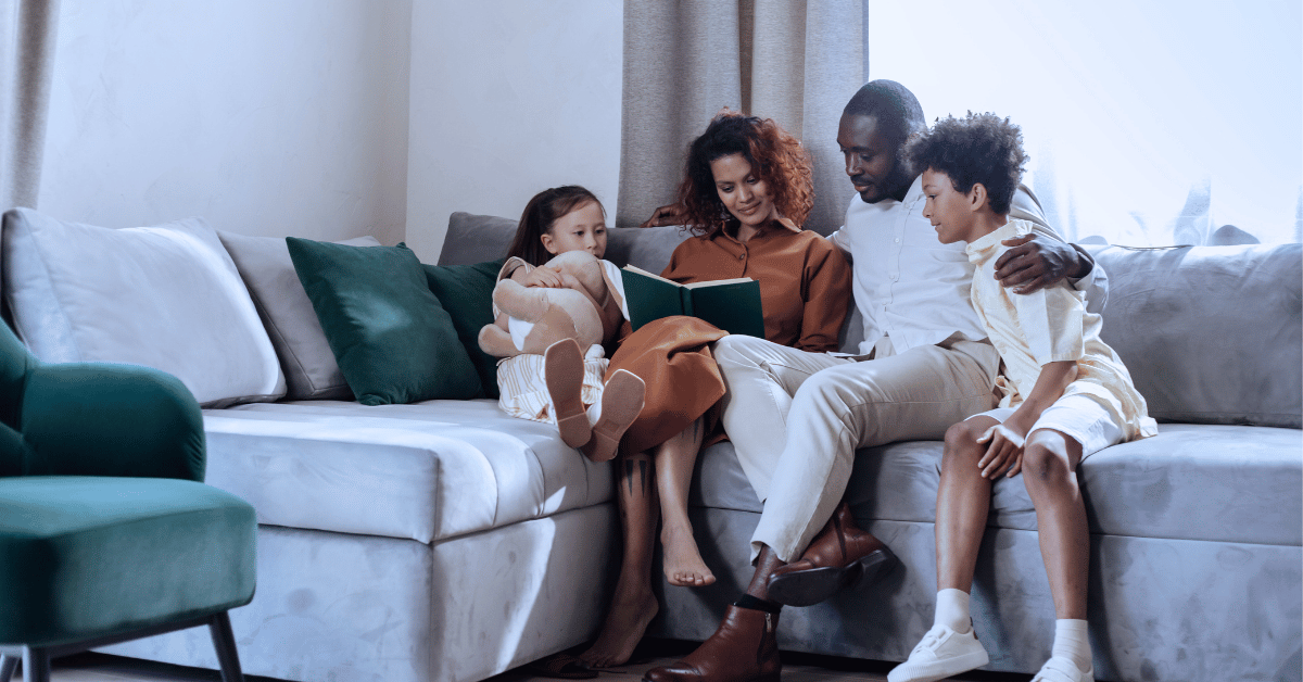 two parents reading to young children on a couch