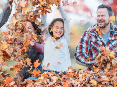 Parents and daughter playing in fall leaves