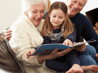 Grandparents reading a book with their granddaughter