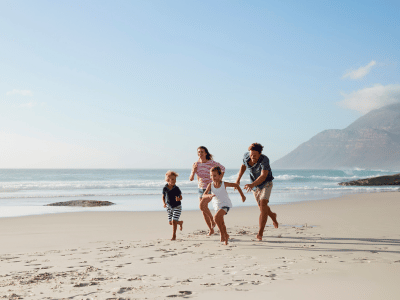 Parents and two kids running on beach