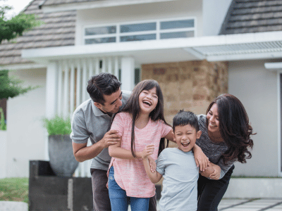 Young family hugging outside home