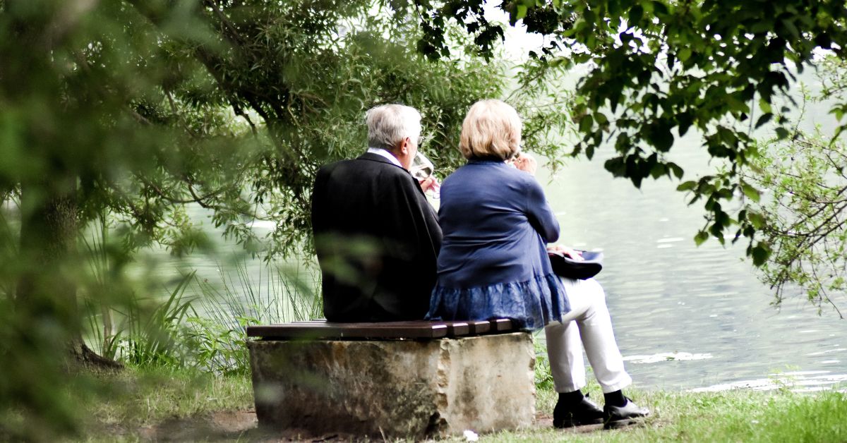 Grandparents sitting on bench beside lake